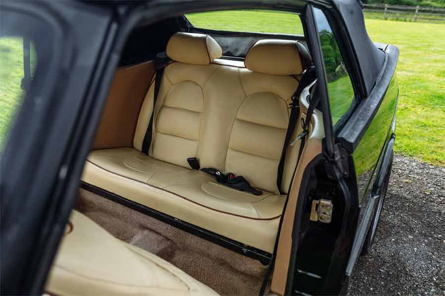 The rear seats of the 1990 Saab 900 T16S FPT Convertible, upholstered in cream leather with brown piping, providing a comfortable and stylish space for passengers.