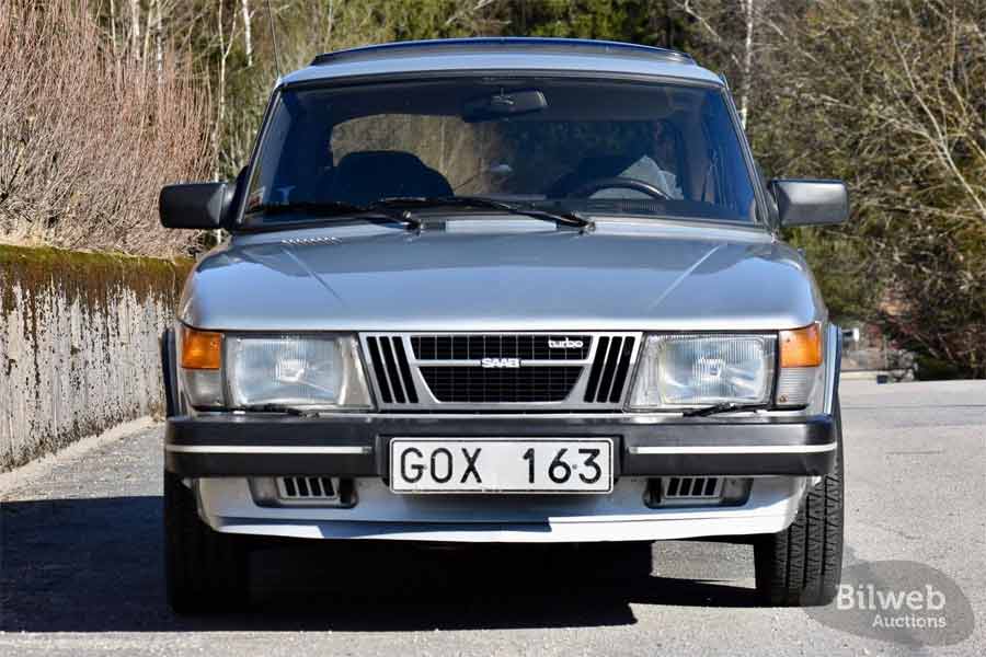 A detailed view of the 1983 Saab 900 Turbo's front grille, showcasing the iconic SAAB emblem and the distinctive Turbo insignia, symbols of its performance legacy and Swedish craftsmanship.