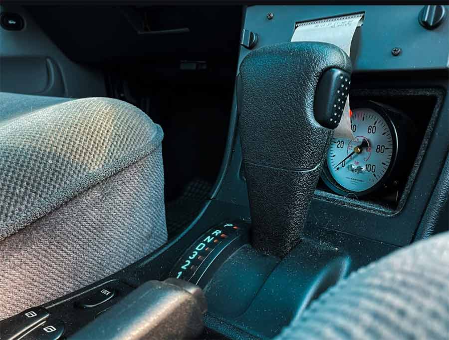 Close-up of the automatic gear stick and friction testing equipment in the 1996 Saab 9000 SFT. This detailed view highlights the pristine condition of the car's interior and the specialized instruments used for runway friction testing. This rare vehicle, preserved by Igor Stankov and his family, showcases Saab's commitment to precision and safety in their unique airport service cars.