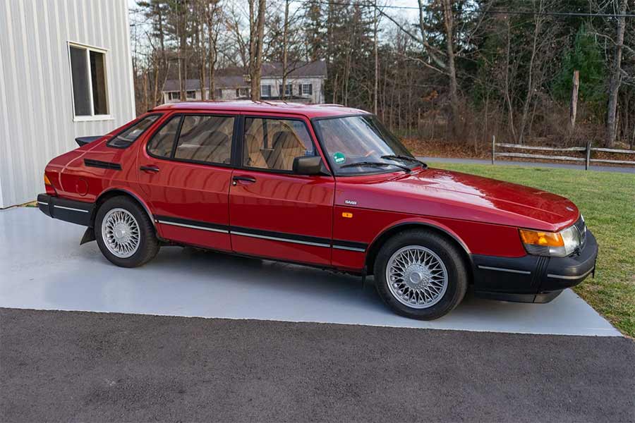 This 1992 Saab 900i in Cherry Red highlights the iconic 5-door hatchback design, factory cross-spoke alloys, and details cherished by true Saab enthusiasts.