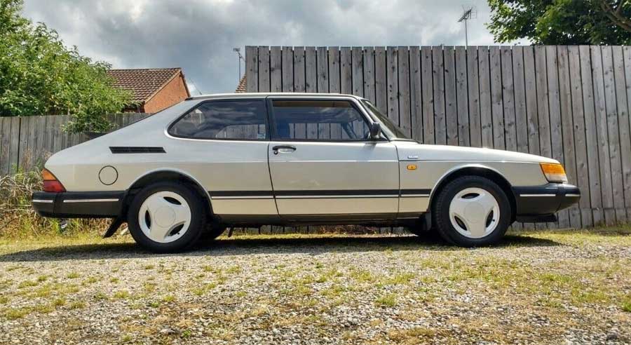 Profile view of the 1991 Saab 900 S Turbo parked outdoors, showcasing its sleek silver exterior and iconic three-spoke wheels.