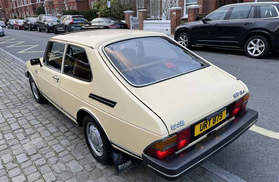 A vintage 1981 Saab 900 GLS parked on a cobblestone street, its classic silhouette and distinctive pale yellow hue echoing the rich heritage of Saab's design legacy.