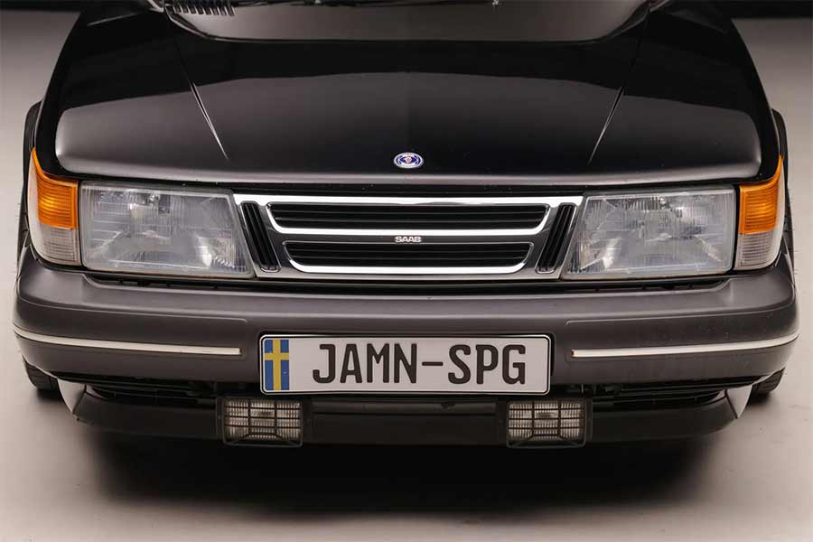 This close-up image of the 1988 Saab 900 Turbo SPG highlights its distinctive front end, featuring the iconic grille, sleek black paint, and the "JAMN-SPG" license plate, perfectly capturing the essence of this rare and highly sought-after classic car.