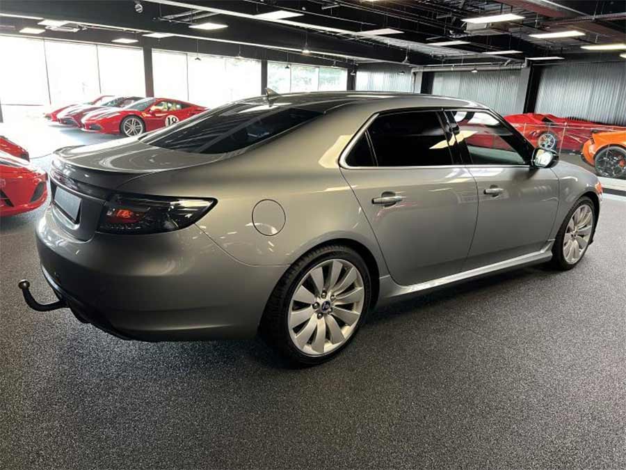 A stunning rear view of the 2010 Saab 9-5 NG Hirsch Performance Edition, showcasing its sleek Granite Grey finish, tinted windows, and 19-inch Hirsch alloy wheels. The upgraded Hirsch sport exhaust and Brembo brakes add both style and performance, making this executive sedan a true collector’s piece.