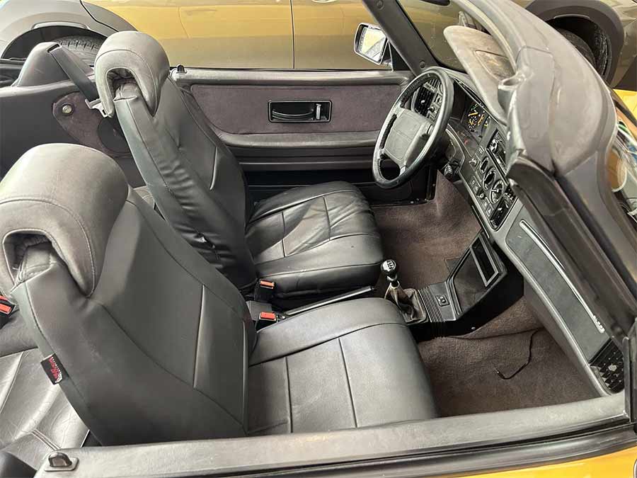 The interior of the 1991 Saab 900 SE Turbo Convertible features gray leather seats and a retrofitted five-speed manual transaxle, combining classic style with enhanced performance.