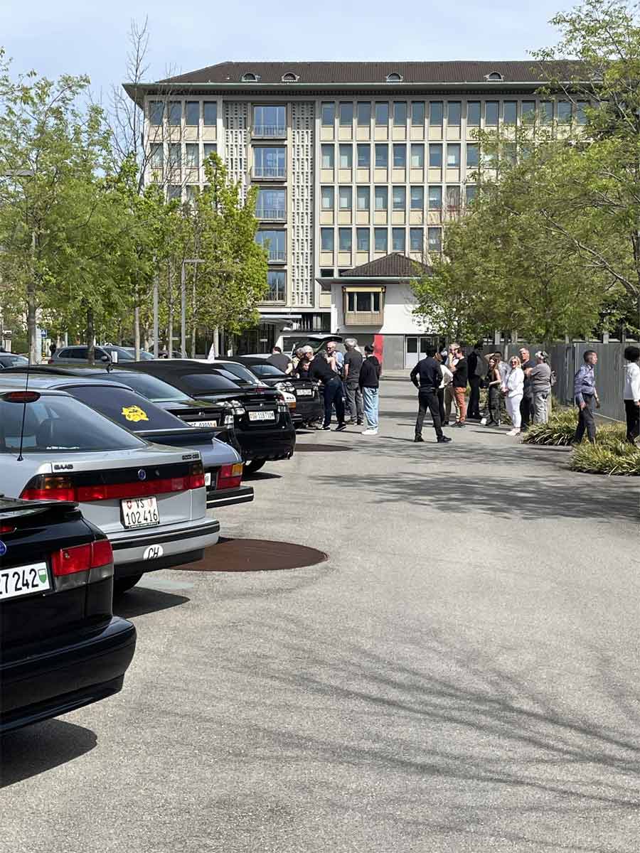 SAAB owners convene in the shadow of the OMEGA watch factory in Switzerland, their cars lined up in preparation for a visit to the esteemed timepiece museums.