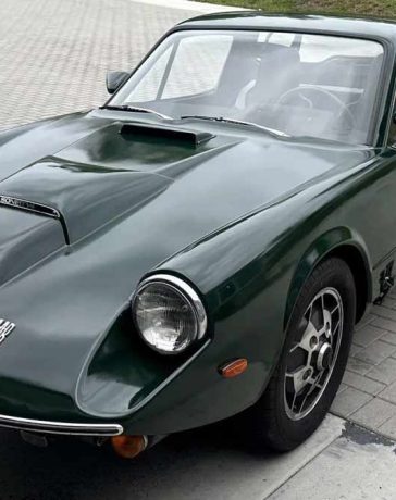 A meticulously restored 1969 Saab Sonett II V4 in a striking green, featuring classic 'soccer-ball' alloy wheels and a distinctive clamshell hood.