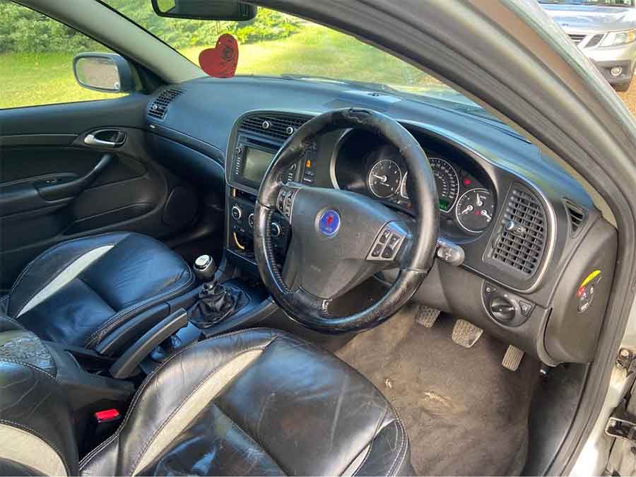 The interior of this 2011 Saab 9-3 Aero Griffin Sportwagon features well-preserved leather seats, though the steering wheel shows noticeable wear.