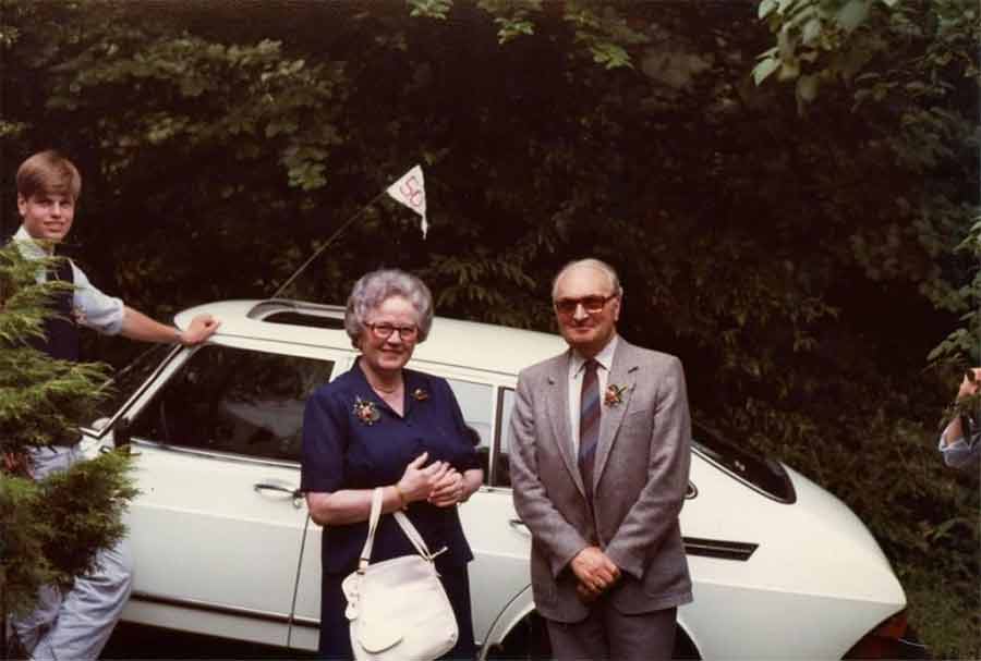 Chris poses next to the family's white Saab 900 during his grandparents' 50th wedding anniversary celebration