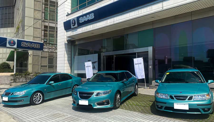 A trio of Saab cars in distinctive Glacier Blue, parked outside the SAC showroom, showcasing the brand's iconic design and color that pays homage to Sweden's frozen landscapes.