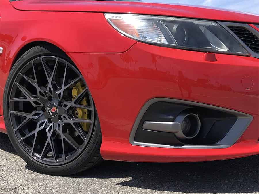 A close-up of this 2008 Saab 9-3 Aero SportCombi’s aggressive front end, featuring the Griffin-style bumper, Turbo X grille, and stunning XO Luxury Phoenix 19” wheels with yellow-painted Brembo calipers—a true blend of performance and aesthetics.