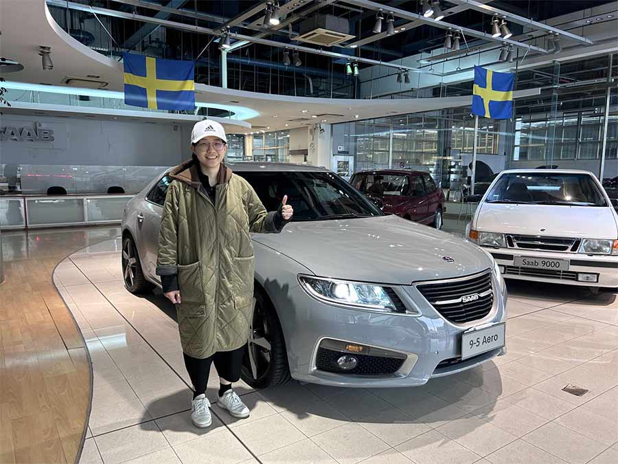 Mr. Ke’s daughter, proudly stands next to the restored Saab 9-5 NG in Brooklyn Gray at SAC's showroom – one of the last remaining active Saab dealerships in the world.Mr. Ke’s daughter, proudly stands next to the restored Saab 9-5 NG in Brooklyn Gray at SAC's showroom – one of the last remaining active Saab dealerships in the world.