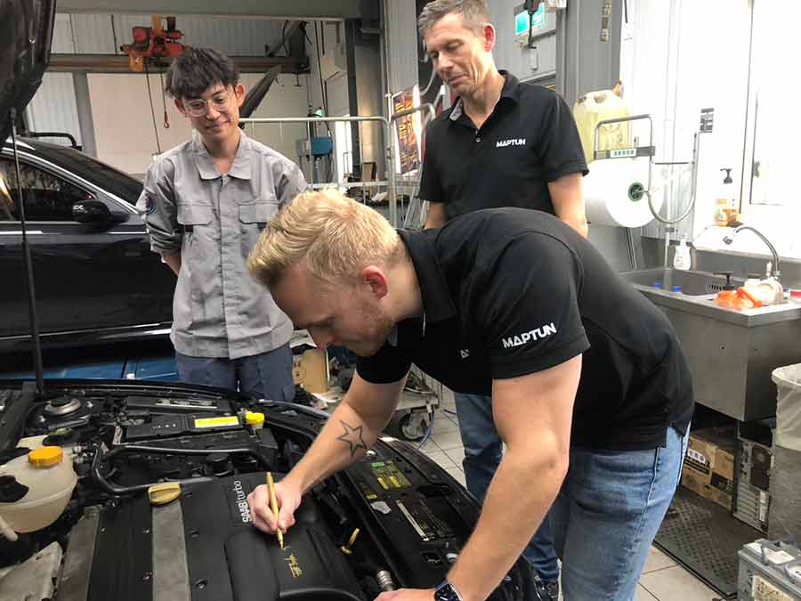 After completing the tuning, Thomas Hellberg from Maptun signs the Saab engine cover, marking the successful performance upgrade with a personal touch.