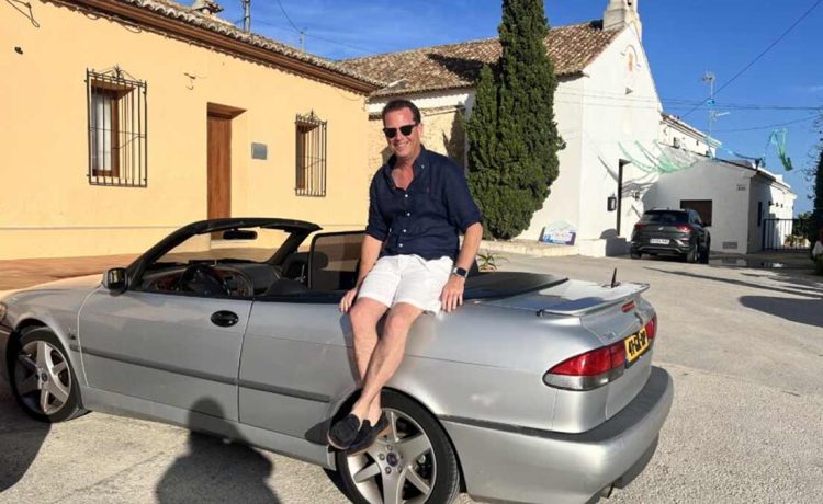 Nicolas Ruis proudly sits on his 2000 Saab 9-3 Aero Convertible, a car he has restored to its former glory and continues to enjoy on memorable road trips across Europe, embodying the passion and dedication of true Saab enthusiasts.