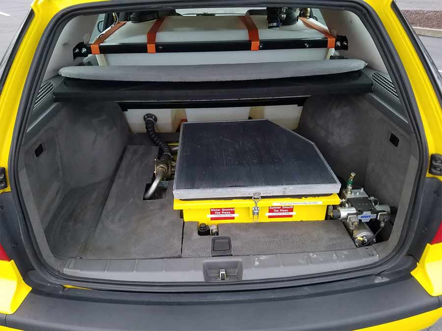 The rear compartment of the 2004 Saab 9-5 Arc Friction Tester, featuring the retrofitted water tank and retractable friction-testing equipment, expertly integrated into the trunk for precise runway surface analysis.