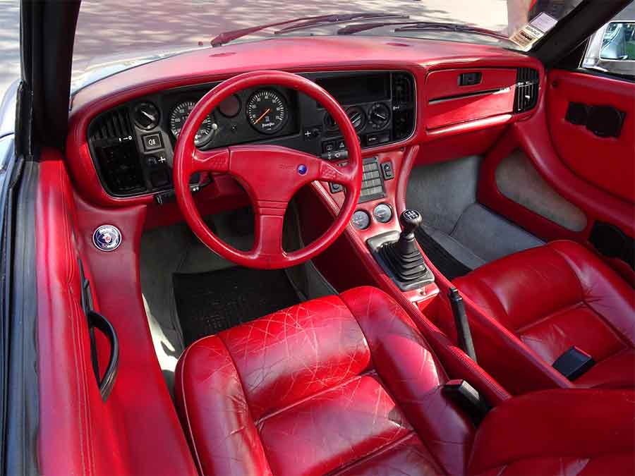 The Saab 900 Speeder features a striking bright red interior, showcasing its custom leather seats, dashboard, and steering wheel, highlighting the unique design and luxurious details of this one-of-a-kind prototype.