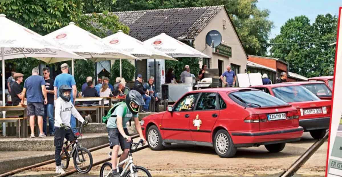 A red Saab 9-3 at the Auto Bild Klassik 1000-Euro Challenge in Worpswede, standing out among vintage competitors during the crowd voting event.