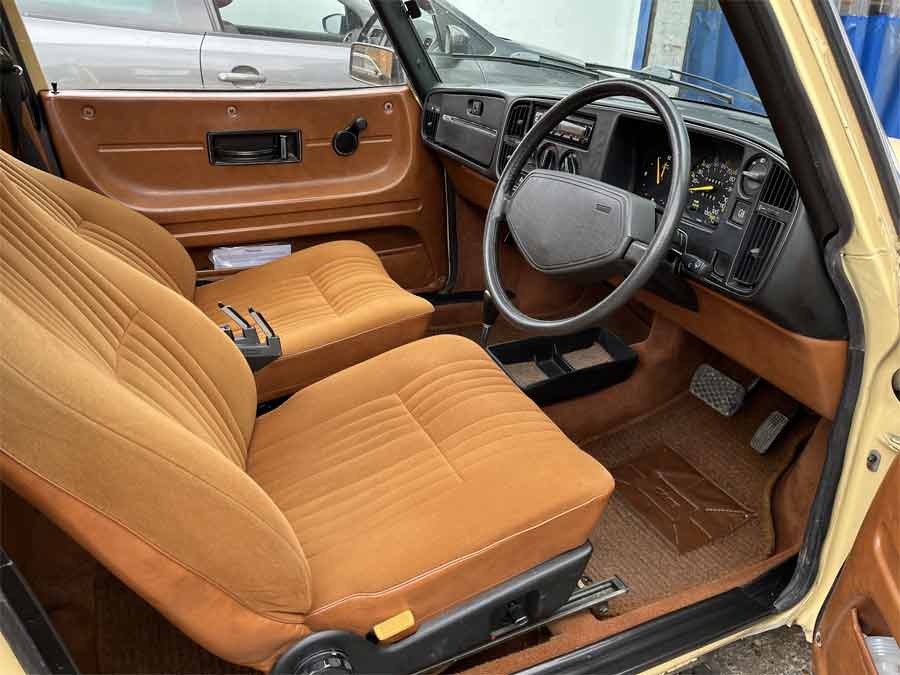 
The immaculate interior of a 1981 Saab 900 GLS, featuring burnt orange upholstery and classic Swedish design, perfectly preserved in its retro glory.