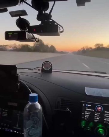 The Saab 9-5 Aero cockpit during the Cannonball Run, equipped with cutting-edge tech and pushing speeds of 140 mph at sunrise.