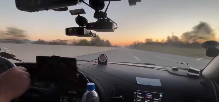 The Saab 9-5 Aero cockpit during the Cannonball Run, equipped with cutting-edge tech and pushing speeds of 140 mph at sunrise.