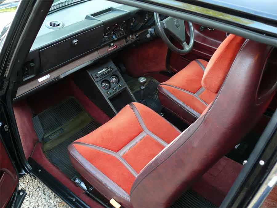 Step into luxury: The red/burgundy interior of the Saab 99 Turbo (DWB 710V) exudes elegance and complements the striking Jet Black exterior, offering a premium driving experience like no other.