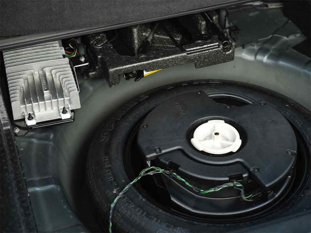 The trunk of the Saab 9-3 SportCombi reveals a meticulously installed BOSE amplifier and a large bass speaker, integrated seamlessly into the spare wheel well. This setup is a testament to the vehicle's harmonious blend of functionality and high-fidelity sound, ensuring that audio quality is not compromised by space constraints. The presence of such premium audio equipment underscores the luxurious and thoughtful design of the Saab, offering an immersive listening experience that complements the drive, no matter the destination.