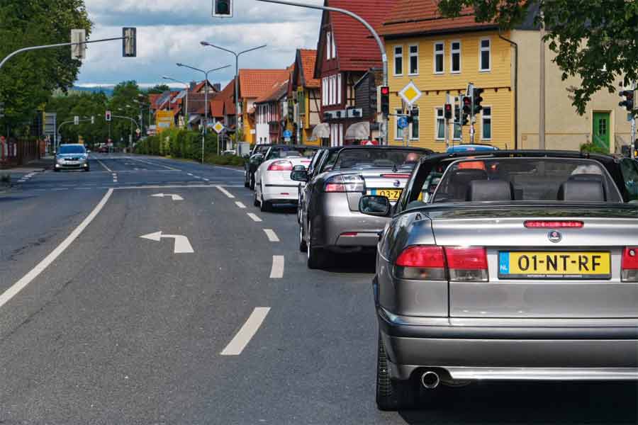 A convoy of Saab convertibles cruises through a charming town during the 2024 Saab Convertible Weekend, illustrating the seamless integration of classic car aesthetics with the everyday rhythm of urban life. (photo by David Joost Kamermans)