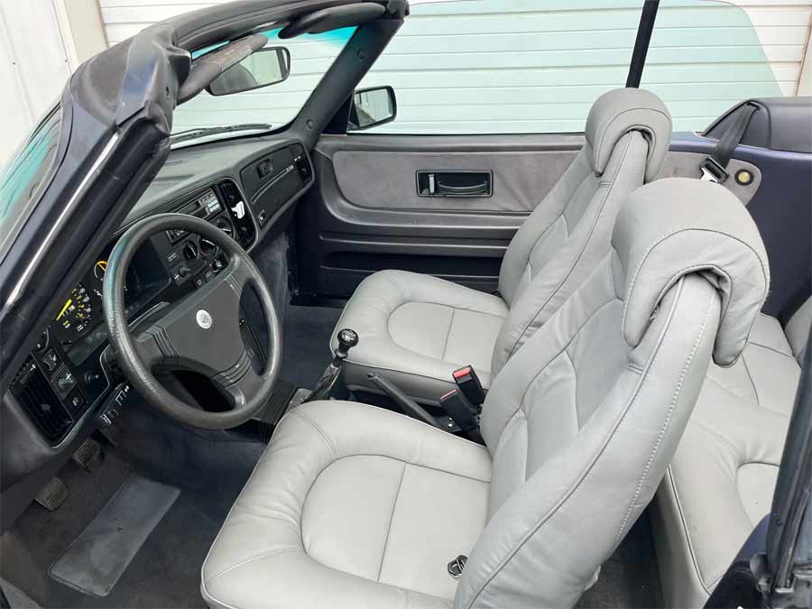 Interior view of the 1988 Saab 900 Turbo Convertible SIS Edition, showcasing its re-trimmed gray leather seats and classic dashboard design, highlighting the car’s well-preserved condition and luxurious features.