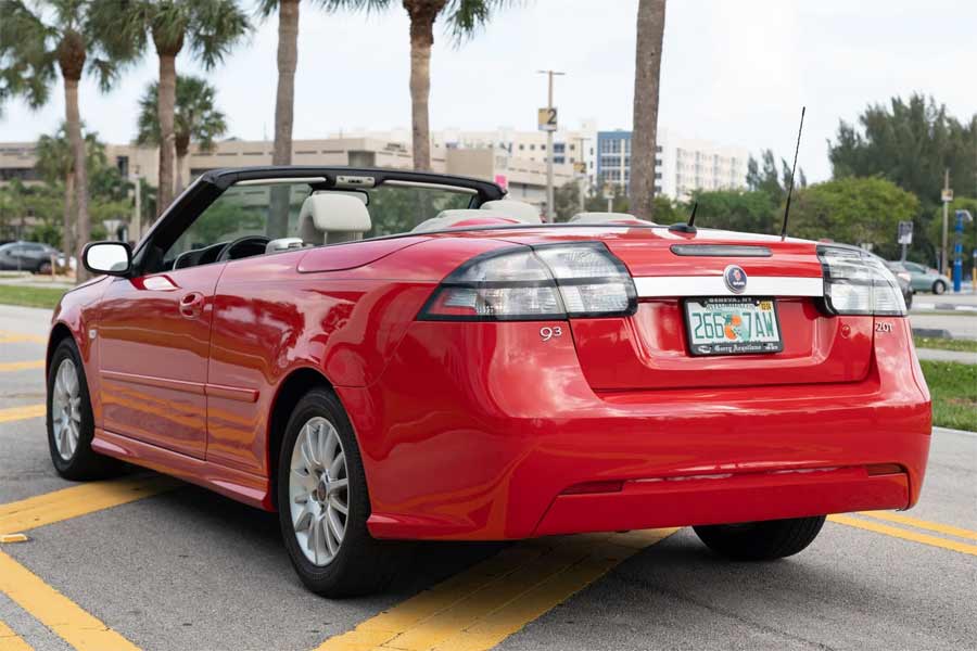 ear view of the 2008 Saab 9-3 Convertible with its top down, embracing the sunny Florida lifestyle amidst a backdrop of clear blue skies.