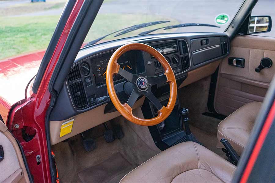 The 1992 Saab 900i interior features a rare wood-rimmed steering wheel, beige leather seats, and Saab’s signature driver-focused cockpit layout cherished by enthusiasts