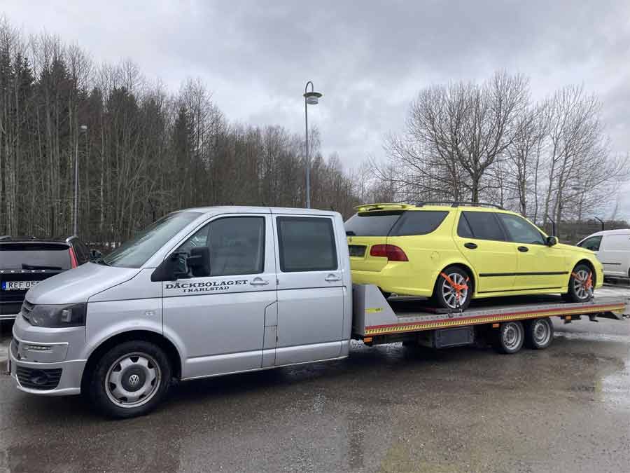 Bringing Home the Ambulance Yellow Saab 9-5: After the Inspection – A captivating sight as the 'Ambulance Yellow' Saab 9-5 rests on a trailer, en route to Peter's home, following a successful inspection that marks another step in its remarkable restoration journey.