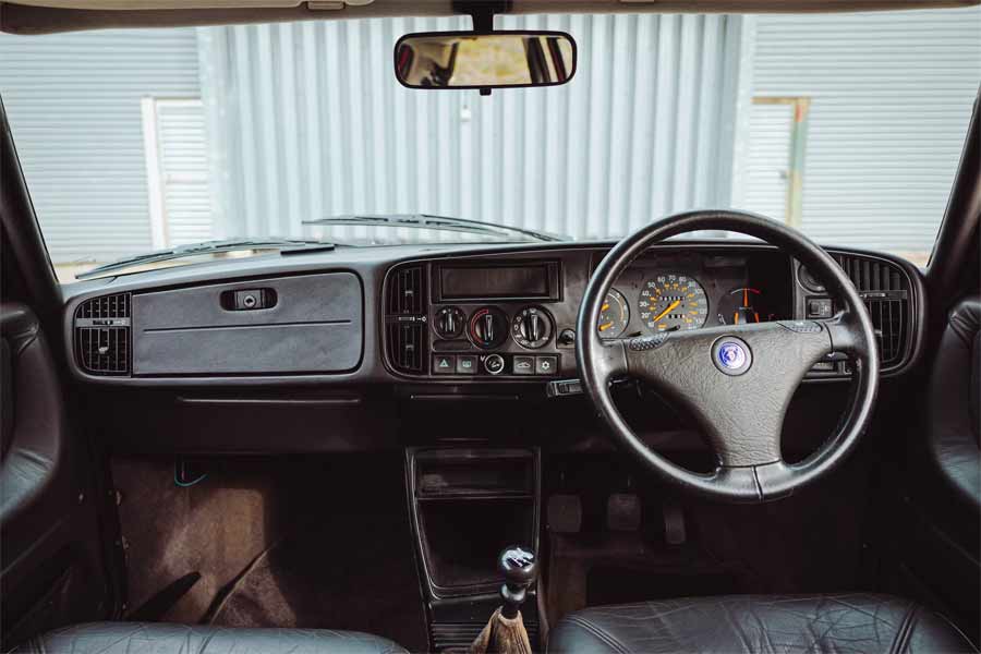 Classic cockpit of the 1993 Saab 900 Turbo Ruby Edition, displaying its well-preserved instrument panel and distinctive steering wheel.