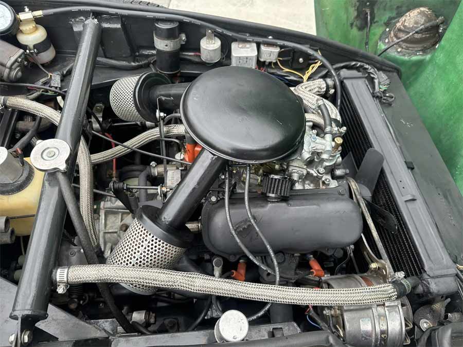 Detail of the overhauled 1.7-liter V4 engine in the 1969 Saab Sonett II, equipped with a Weber carburetor and stainless-steel coolant hoses for enhanced performance.