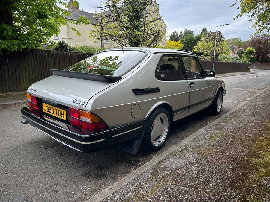 Angled rear view of the 1991 Saab 900 S Turbo parked on a suburban street, showcasing its classic design and sporty rear spoiler.