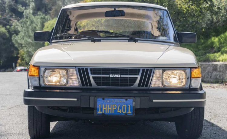 1983 Saab 900 in Ivory, showcasing its classic silhouette and timeless design on a serene road, embodying the joy of driving a vintage masterpiece.