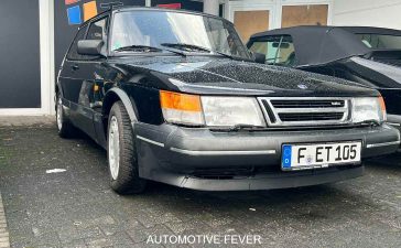 A well-preserved SAAB 900 Turbo 16 S, showcasing its iconic angular design and turbocharged performance, parked at an automotive event in Germany. The sleek black exterior and classic styling make this model a true standout in the world of vintage cars. Photo credit: Automotive Fever.