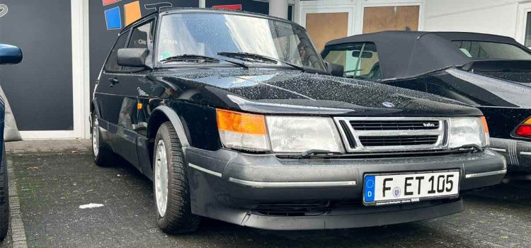 A well-preserved SAAB 900 Turbo 16 S, showcasing its iconic angular design and turbocharged performance, parked at an automotive event in Germany. The sleek black exterior and classic styling make this model a true standout in the world of vintage cars. Photo credit: Automotive Fever.