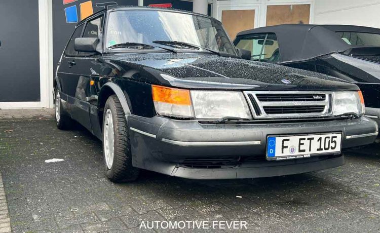 A well-preserved SAAB 900 Turbo 16 S, showcasing its iconic angular design and turbocharged performance, parked at an automotive event in Germany. The sleek black exterior and classic styling make this model a true standout in the world of vintage cars. Photo credit: Automotive Fever.