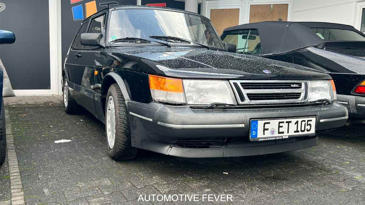 A well-preserved SAAB 900 Turbo 16 S, showcasing its iconic angular design and turbocharged performance, parked at an automotive event in Germany. The sleek black exterior and classic styling make this model a true standout in the world of vintage cars. Photo credit: Automotive Fever.