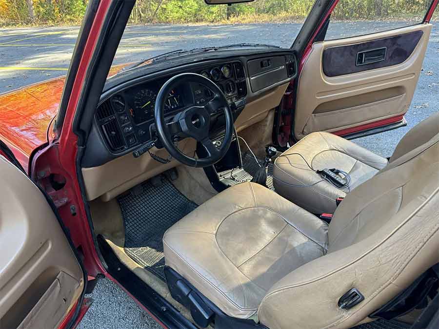 The refreshed interior of the 1990 Saab 900 Turbo SPG combines tan leather upholstery with a classic Saab layout, featuring AEM auxiliary gauges and a short-throw shifter for a driver-focused experience.