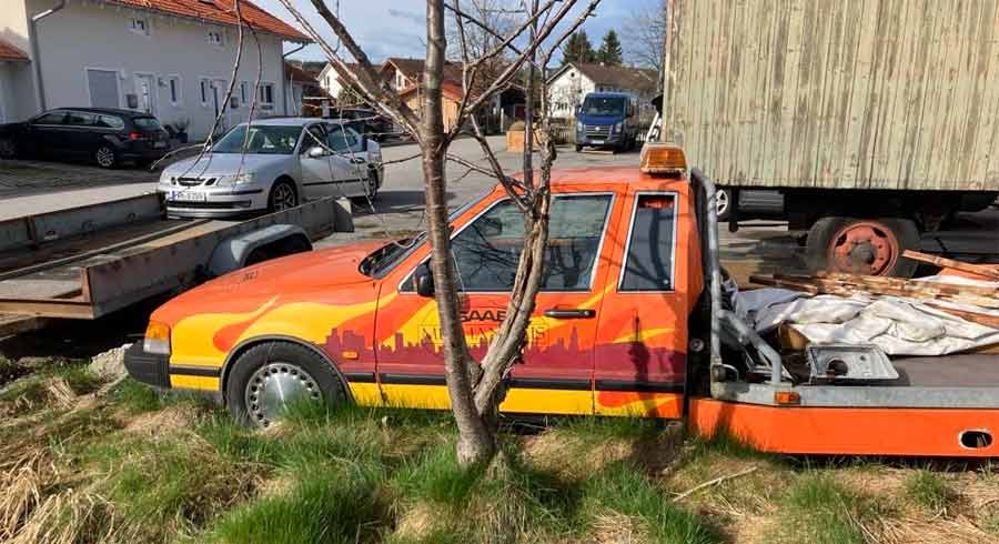 "A vivid echo of its industrious past, the Saab 9000 Auto Transporter rests, its vibrant colors contrast against the stillness of its surroundings, a silent call to restore its dynamic legacy.