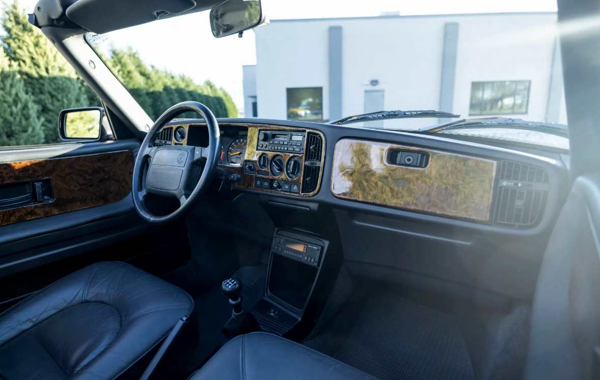 A refined cockpit featuring custom wood accents, heated leather seats, and a five-speed manual shifter—showcasing the 900’s unmistakable driver-centric charm.