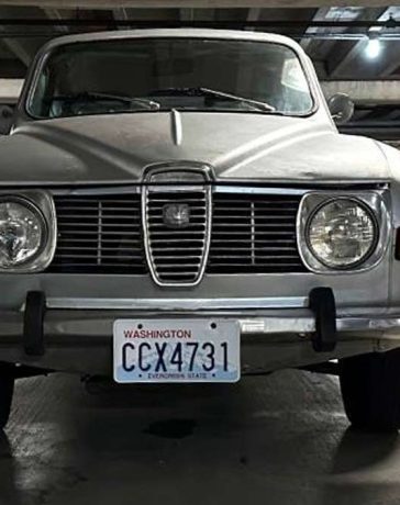 Vintage Charm in Modern Times: The 1972 Saab 96 V4 stands proudly in a contemporary parking garage, its classic features a stark, beautiful contrast to the modern vehicles that flank it."