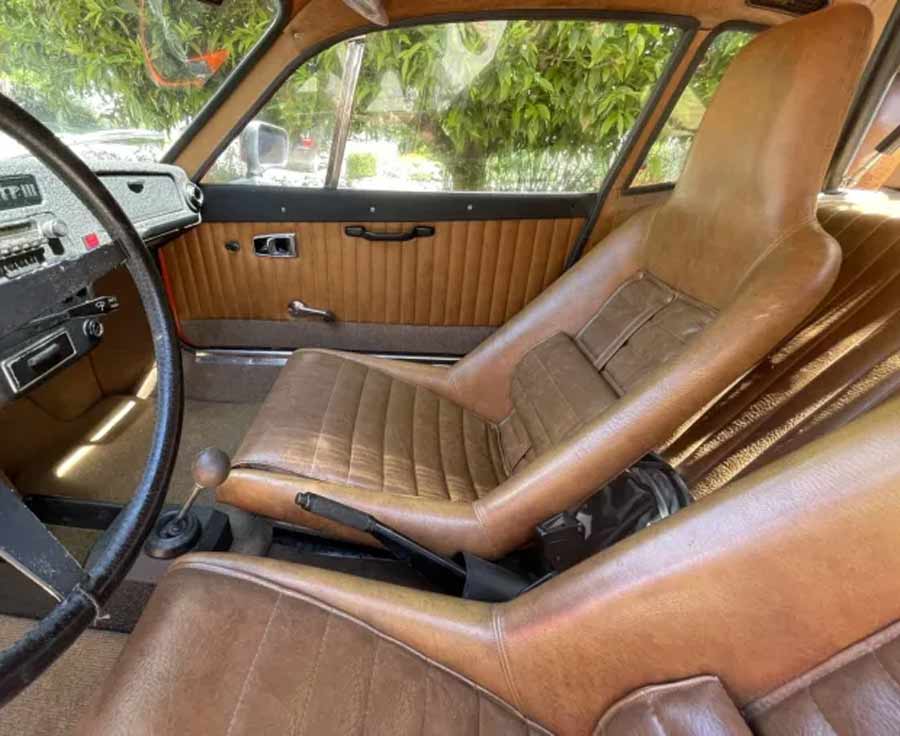 Interior glimpse of the 1973 Saab Sonett III, featuring the original tan vinyl seats with cloth inserts, and classic wooden dashboard accents.