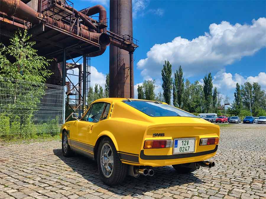  Rear view of the 1972 Saab Sonett III, now sporting a vibrant yellow finish with black stripes. This classic sports car, originally red-orange, showcases its beautifully restored condition and timeless design