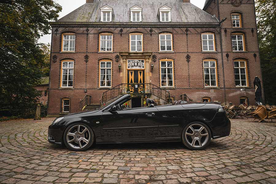 The KCPerformance Saab 9-3 Turbo X Convertible, a striking blend of heritage and innovation, showcased against a classic European manor backdrop.