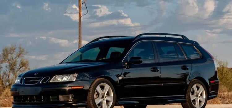 a well-maintained black 2006 Saab 9-3 Aero SportCombi parked outdoors. The car has a sleek design, featuring five-spoke alloy wheels, roof rails, and a sunroof. The front of the car is distinct with its Xenon headlights and fog lights.