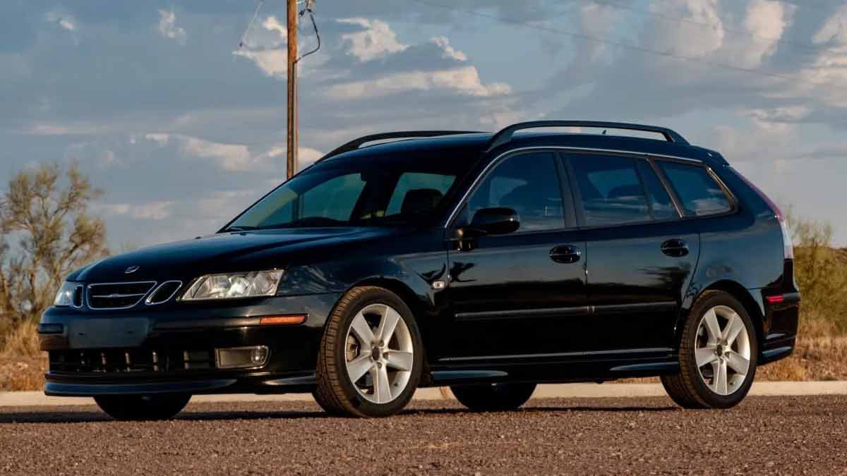 a well-maintained black 2006 Saab 9-3 Aero SportCombi parked outdoors. The car has a sleek design, featuring five-spoke alloy wheels, roof rails, and a sunroof. The front of the car is distinct with its Xenon headlights and fog lights.